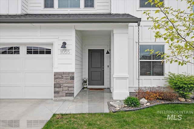 entrance to property with a garage, board and batten siding, and stone siding