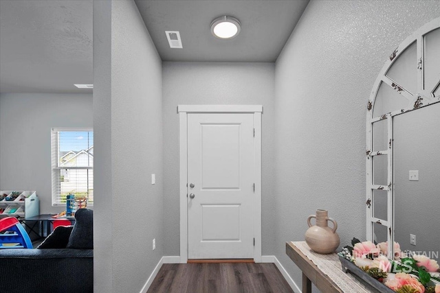 mudroom featuring visible vents, a textured wall, dark wood-style floors, and baseboards