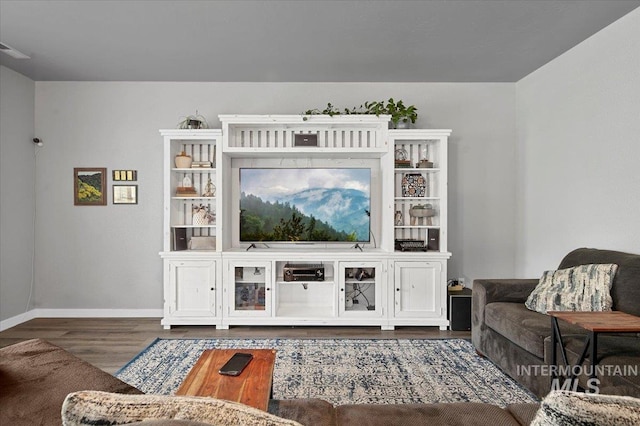 living area featuring visible vents, wood finished floors, and baseboards
