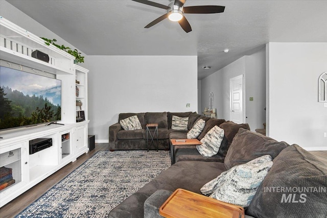 living area featuring baseboards, a ceiling fan, and dark wood-style flooring