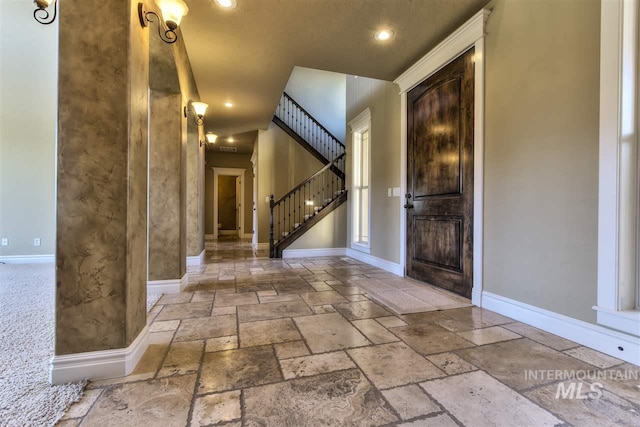 entryway featuring stairway, stone tile floors, and baseboards