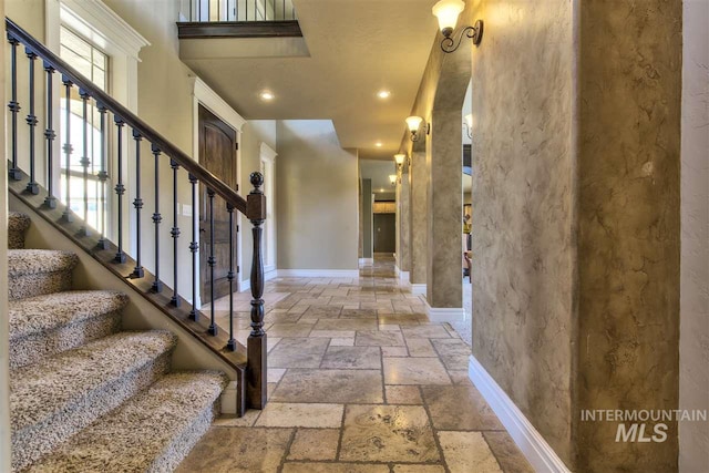 entrance foyer with stone tile floors, recessed lighting, stairs, and baseboards