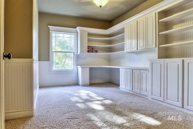 interior space with built in desk and light colored carpet