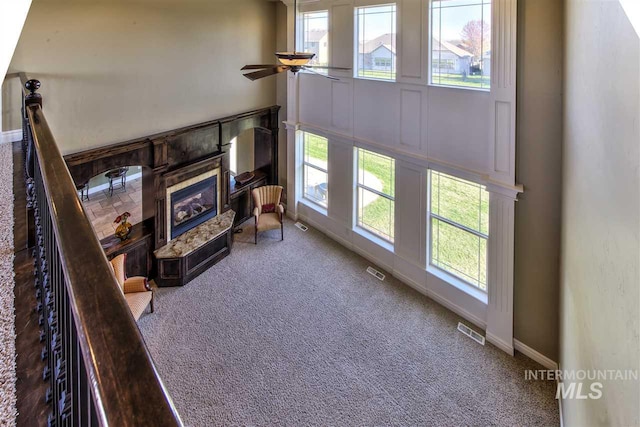 carpeted living area featuring visible vents, a healthy amount of sunlight, and ceiling fan