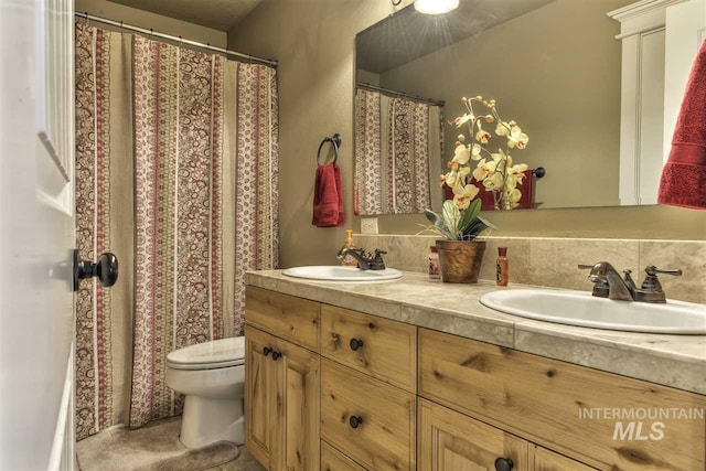 bathroom with a sink, toilet, and double vanity