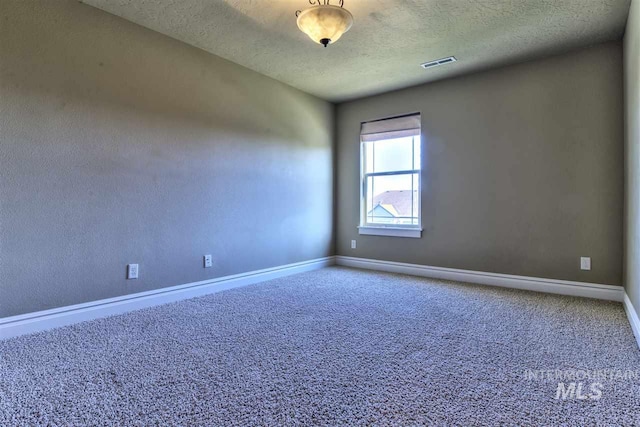 spare room featuring visible vents, carpet floors, a textured ceiling, and baseboards