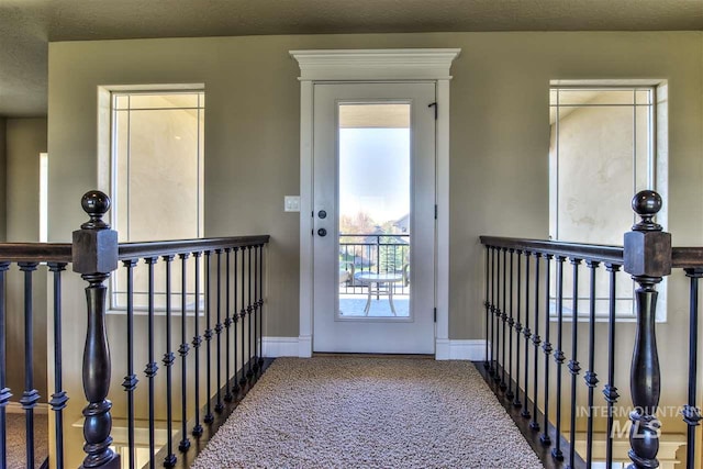 doorway to outside with carpet flooring and baseboards