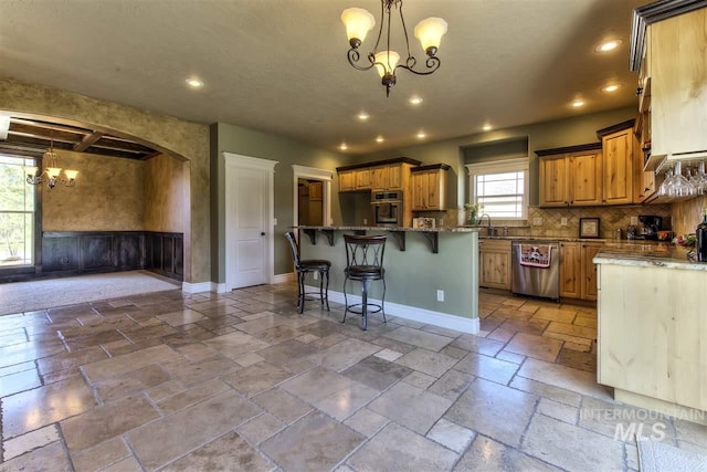 kitchen featuring stone tile floors, baseboards, an inviting chandelier, recessed lighting, and stainless steel appliances