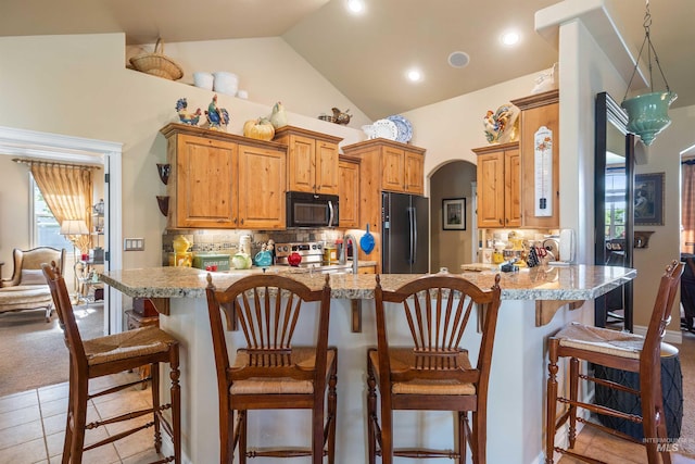 455 Coiner Cir, Twin Falls, ID 83301 - kitchen with black appliances, a kitchen bar, arched walkways, backsplash, and a peninsula