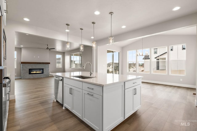 kitchen with a sink, a ceiling fan, dishwasher, a glass covered fireplace, and open floor plan