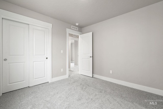 unfurnished bedroom featuring baseboards, visible vents, a closet, and carpet