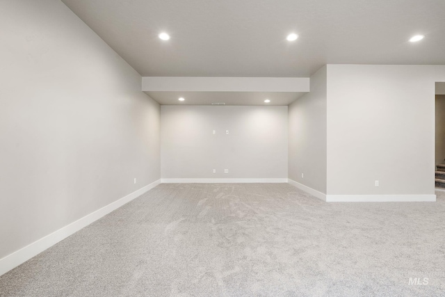 spare room with baseboards, recessed lighting, and light colored carpet