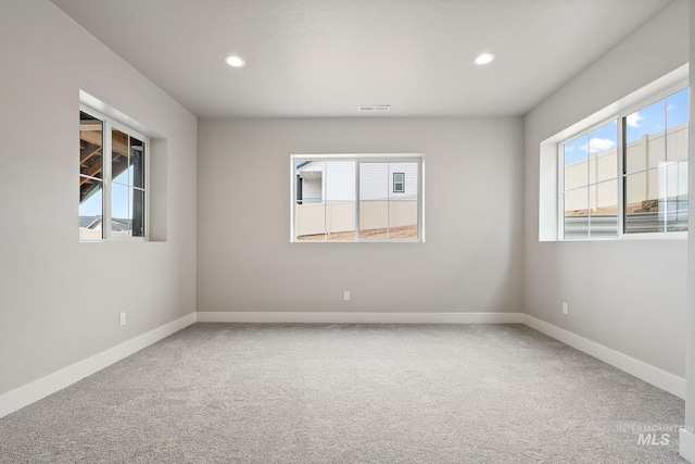 carpeted empty room featuring baseboards, visible vents, and recessed lighting
