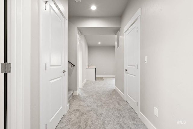 hallway with baseboards, recessed lighting, and light carpet
