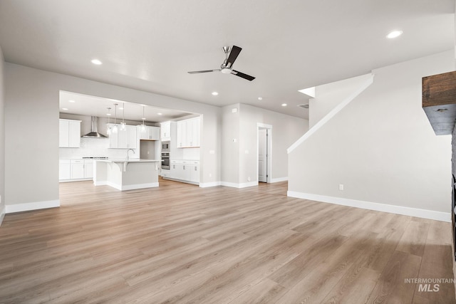 unfurnished living room with baseboards, recessed lighting, a ceiling fan, and light wood finished floors