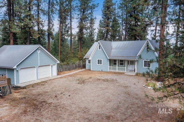 ranch-style house featuring metal roof, fence, dirt driveway, a garage, and covered porch