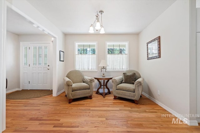 sitting room with baseboards, light wood-type flooring, and a notable chandelier
