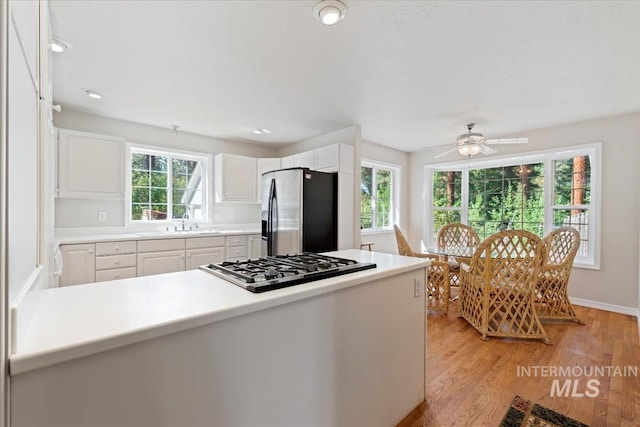 kitchen featuring white cabinetry, a ceiling fan, stainless steel fridge, gas cooktop, and light wood-style flooring