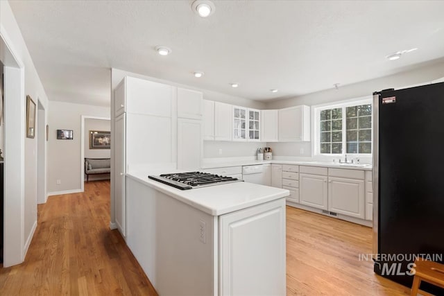 kitchen with light countertops, dishwasher, white cabinetry, gas stovetop, and freestanding refrigerator