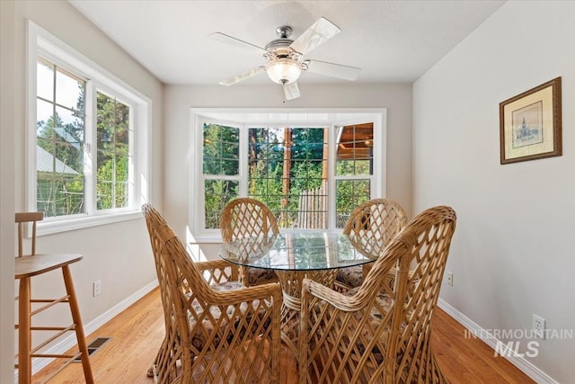 dining space featuring baseboards, light wood-style flooring, and a ceiling fan