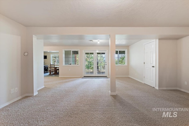 carpeted spare room featuring baseboards and a textured ceiling