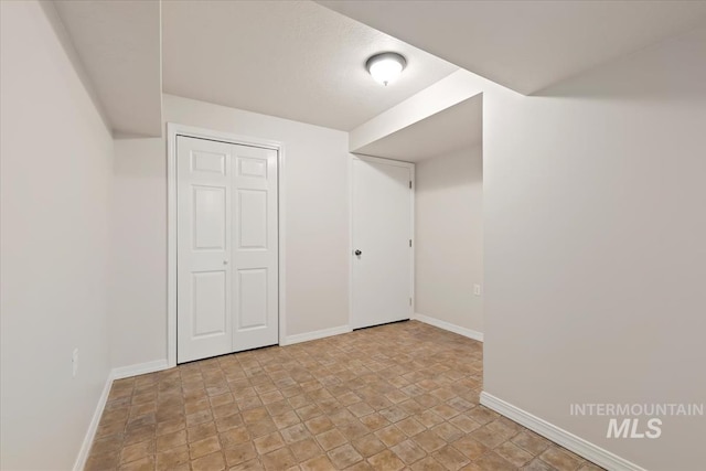 finished below grade area with baseboards and stone finish floor