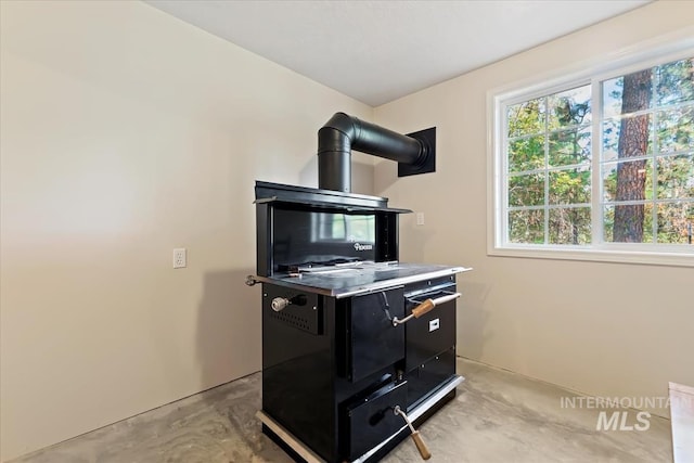 kitchen featuring concrete flooring, dark cabinets, and a wood stove