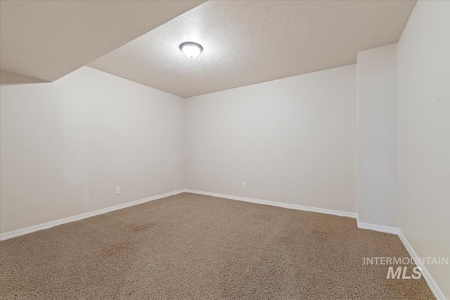 empty room with baseboards, a textured ceiling, and carpet