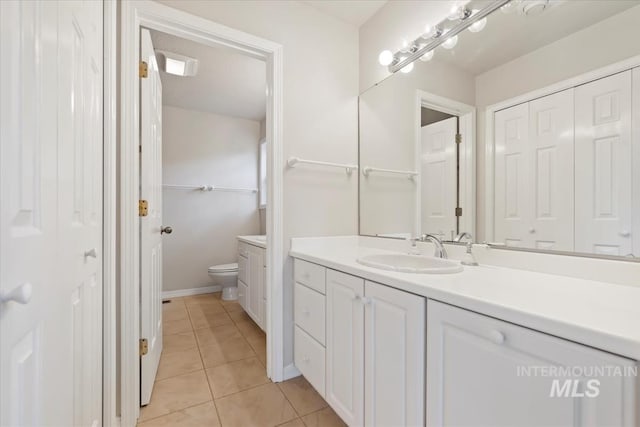 bathroom with a closet, baseboards, toilet, vanity, and tile patterned flooring