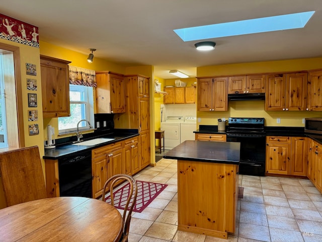 kitchen with black appliances, a skylight, a kitchen island, and washer and dryer