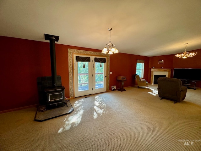 living room featuring carpet, vaulted ceiling, a wood stove, a fireplace, and a chandelier