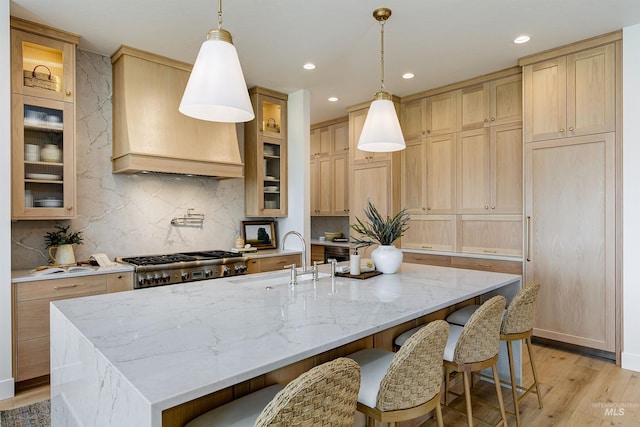 6203 W Estuary St, Eagle, ID 83616 - kitchen featuring a sink, light wood finished floors, custom exhaust hood, a center island with sink, and decorative backsplash