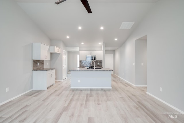 kitchen featuring ceiling fan, a sink, white cabinets, light wood-style floors, and stainless steel microwave