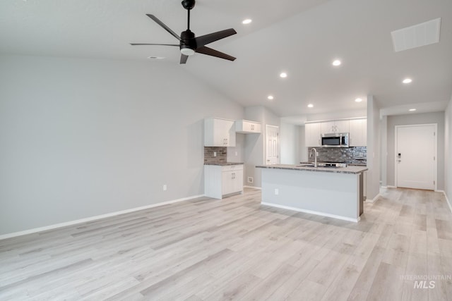 kitchen with stainless steel microwave, visible vents, open floor plan, and decorative backsplash