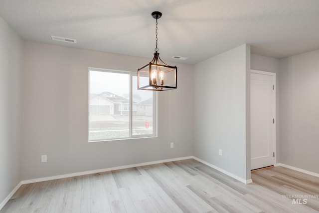 unfurnished room featuring visible vents, baseboards, a chandelier, and light wood-style flooring