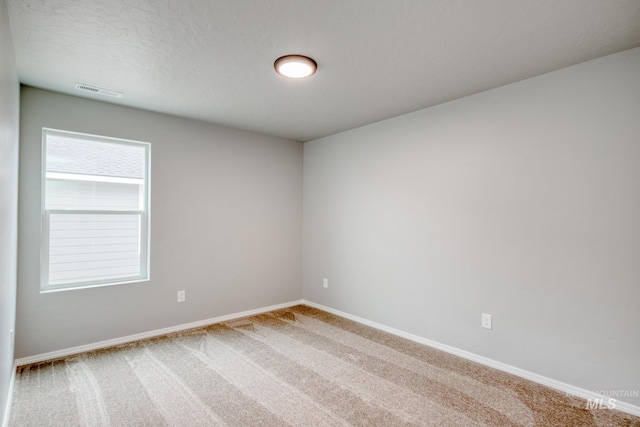 empty room featuring visible vents, carpet, and baseboards