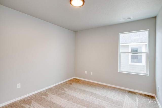 empty room featuring carpet flooring, baseboards, and visible vents