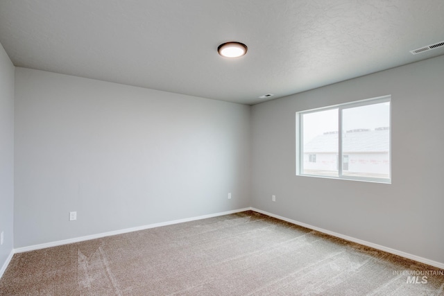 carpeted empty room featuring baseboards, visible vents, and a textured ceiling