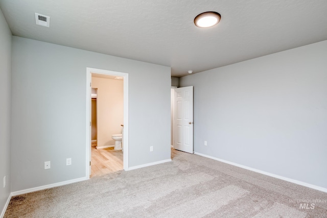 unfurnished bedroom with visible vents, baseboards, carpet flooring, ensuite bathroom, and a textured ceiling