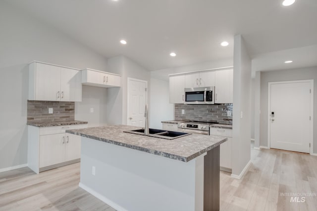 kitchen featuring white cabinets, appliances with stainless steel finishes, light wood-type flooring, and a sink