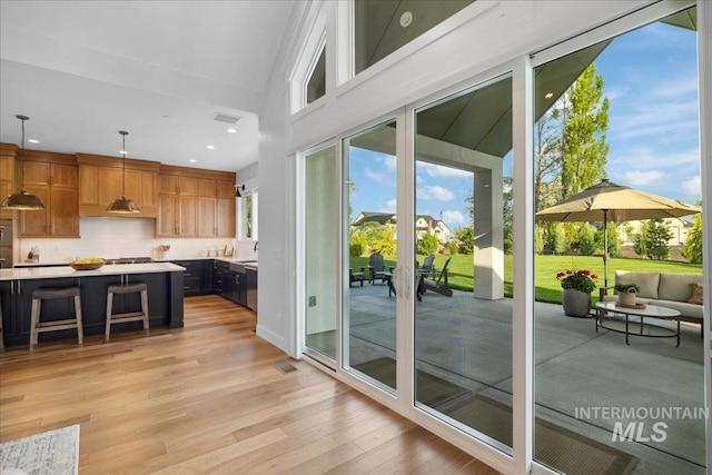 8848 Overunder Ln, Middleton, ID 83644 - kitchen with light countertops, light wood-style floors, backsplash, pendant lighting, and a kitchen breakfast bar