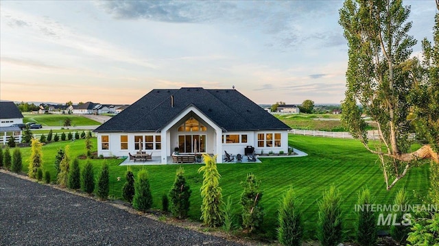 8848 Overunder Ln, Middleton, ID 83644 - back of property featuring a patio, a lawn, a shingled roof, and stucco siding