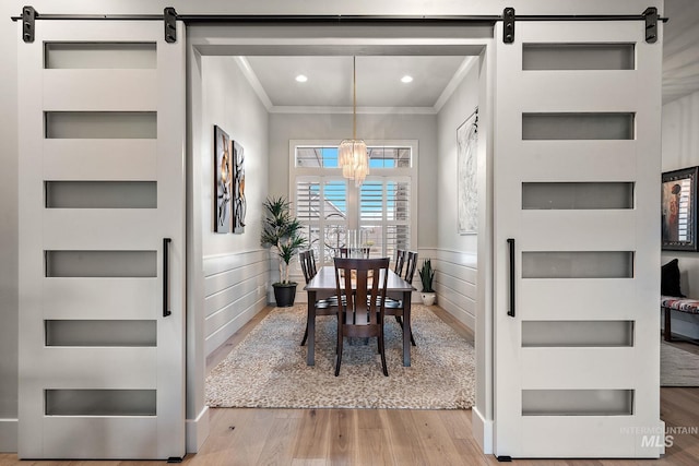 dining room featuring built in features, ornamental molding, and a barn door