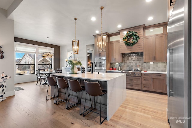 kitchen with a breakfast bar, light wood-style floors, light countertops, appliances with stainless steel finishes, and tasteful backsplash