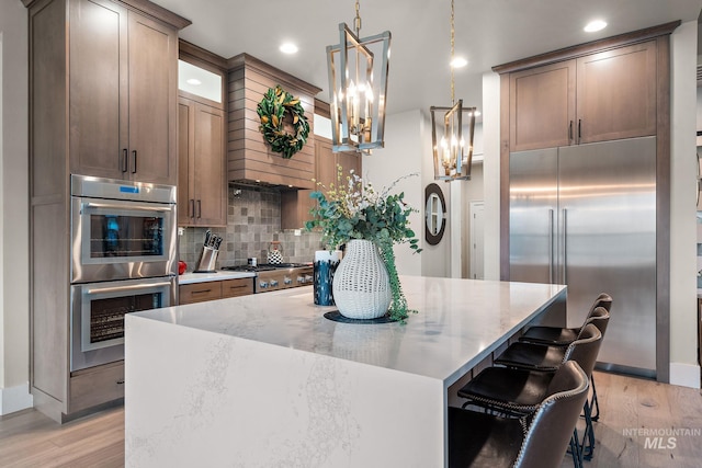 kitchen with stainless steel appliances, a center island, light wood-style flooring, and decorative backsplash