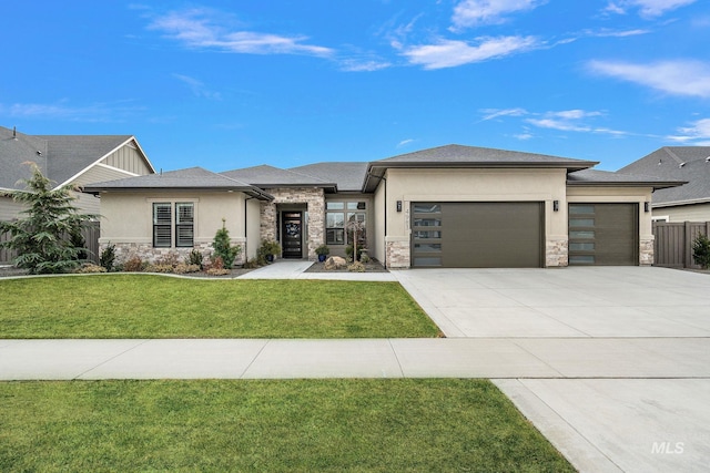 prairie-style house with stucco siding, concrete driveway, a front yard, a garage, and stone siding