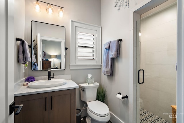 bathroom with a stall shower, vanity, toilet, and baseboards