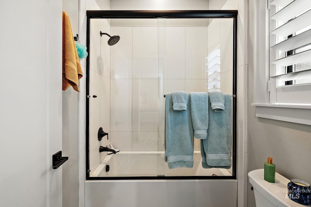 bathroom featuring bath / shower combo with glass door and toilet