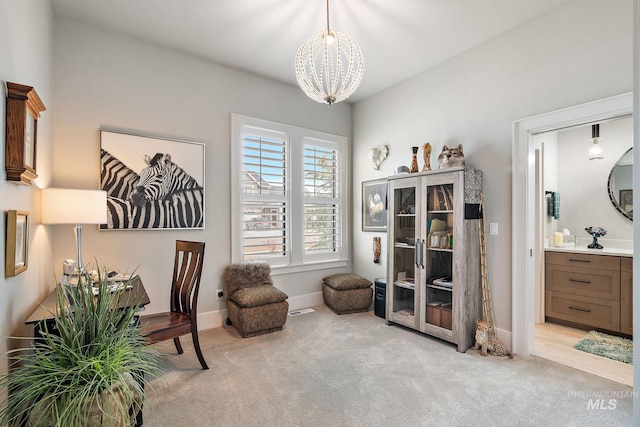 sitting room with a notable chandelier, baseboards, and carpet flooring