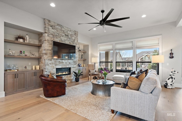 living room with a ceiling fan, light wood-type flooring, a fireplace, and recessed lighting